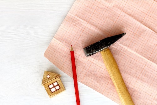 Graph paper with a pencil, hammer and miniature house